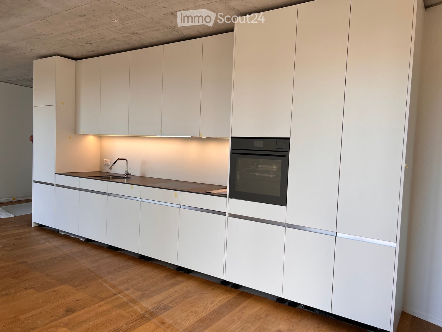 Modern kitchen with white cabinets, a dark countertop, a sink with a faucet, and an oven.