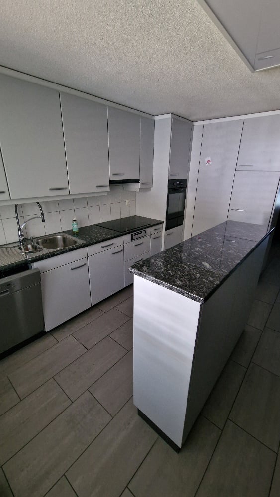 Modern kitchen with white cabinets, granite countertop, stainless steel sink, faucet, oven, and dishwasher.