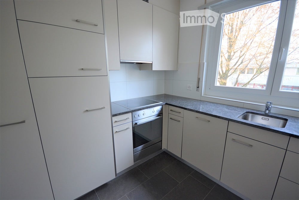 Modern kitchen with white cabinets, stainless steel stove, sink, and countertop.