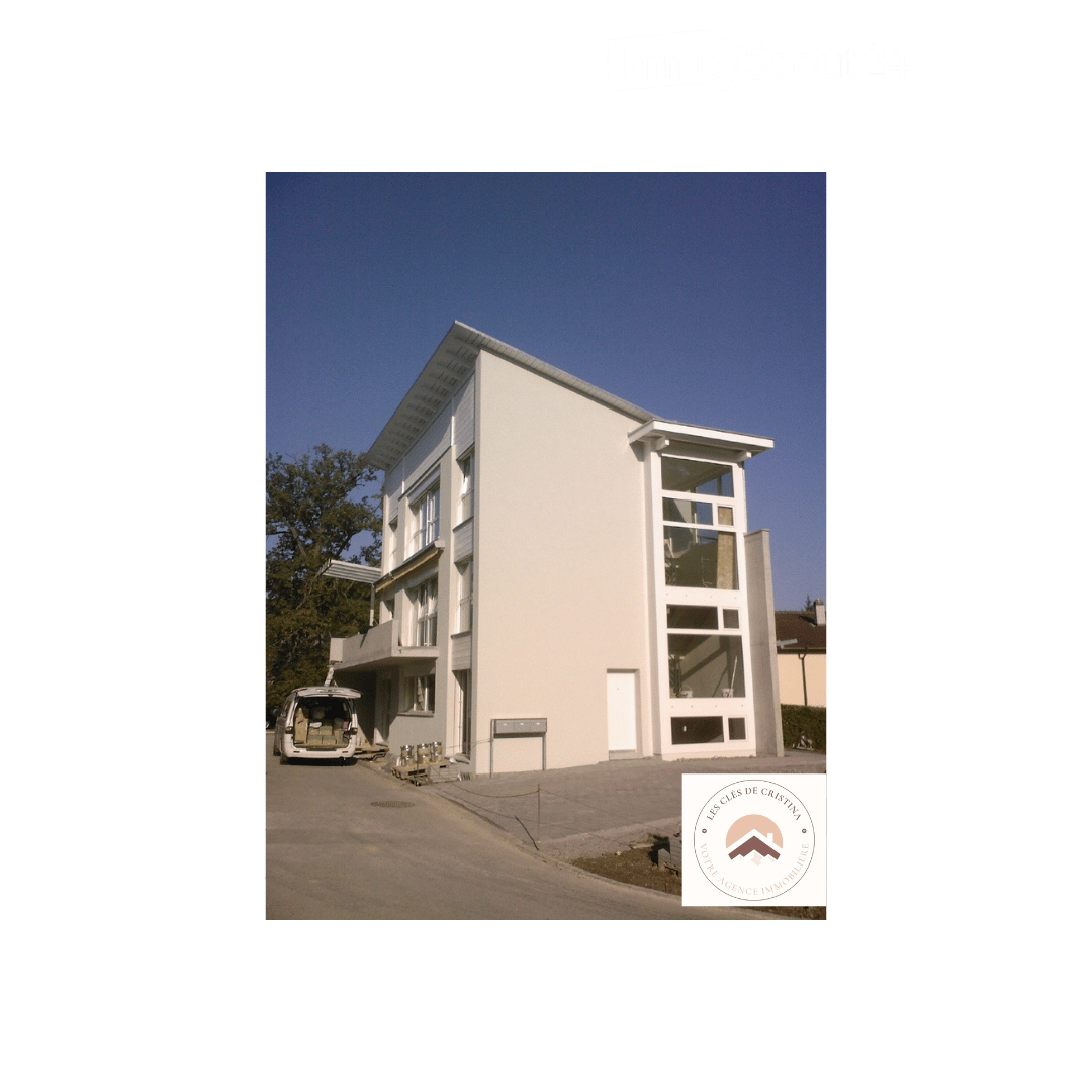 Modern two-story building with white exterior, large windows, and a balcony on the upper level.