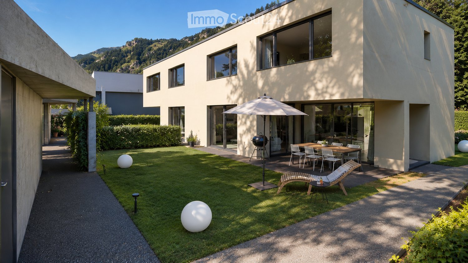 Modern house with a well-maintained garden, featuring a patio with a dining set, lounge chairs, and a barbecue. The garden includes a lawn, decorative spheres, and a pathway leading to the house.
