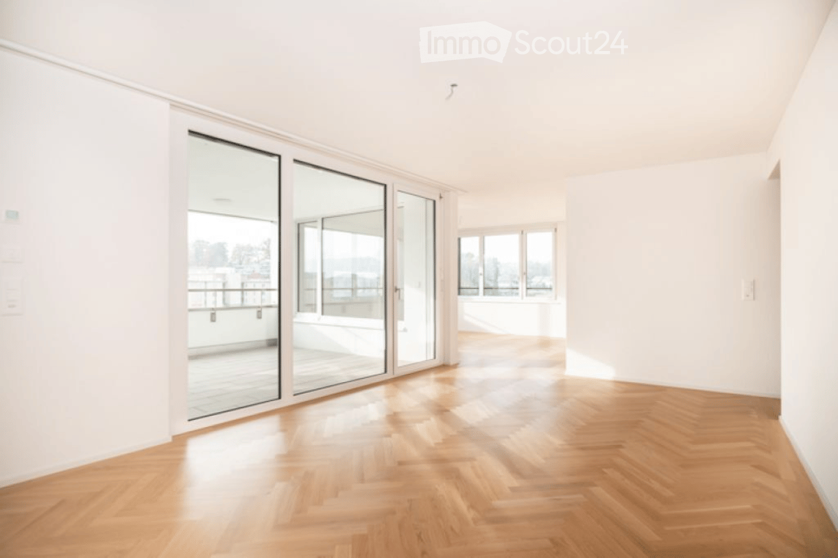 Empty room with wooden flooring, large glass sliding doors leading to a balcony, and white walls.