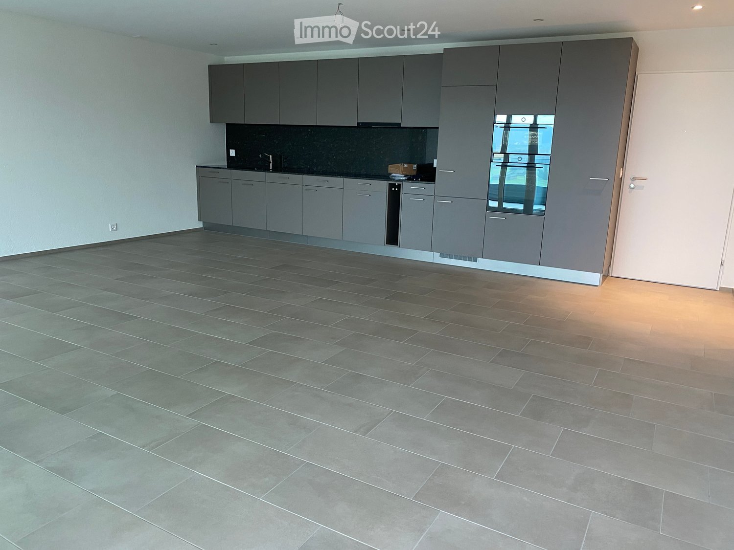 modern kitchen with gray cabinets, tiled floor, black countertop, stainless steel sink, oven, dishwasher