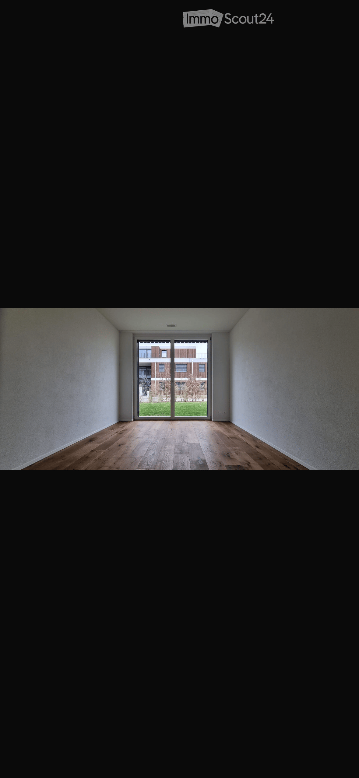 Empty room with wooden flooring, white walls, and large sliding glass doors leading to a green outdoor area.