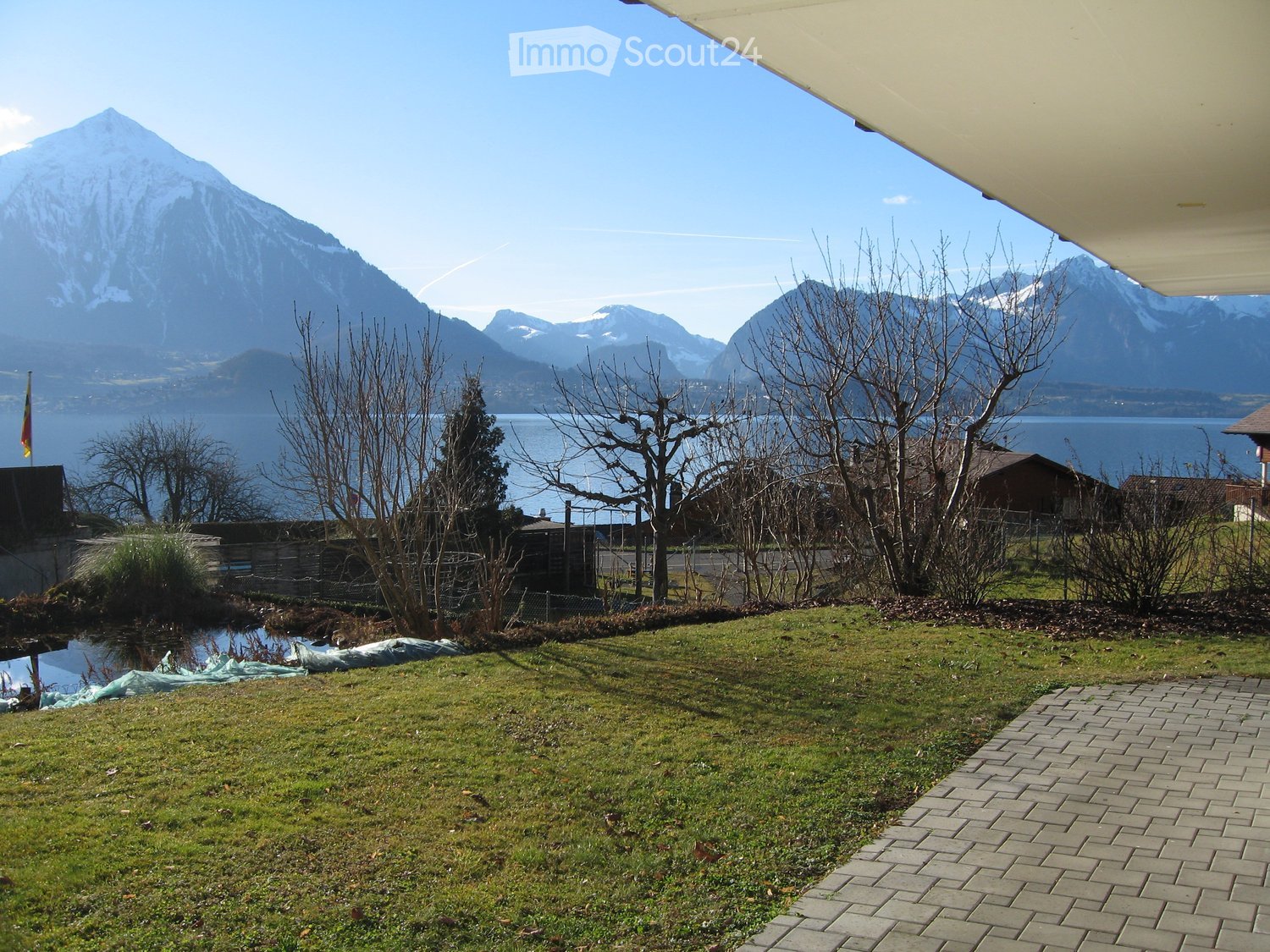 large open lawn area, small path leading up to balcony, flagpole, and lake