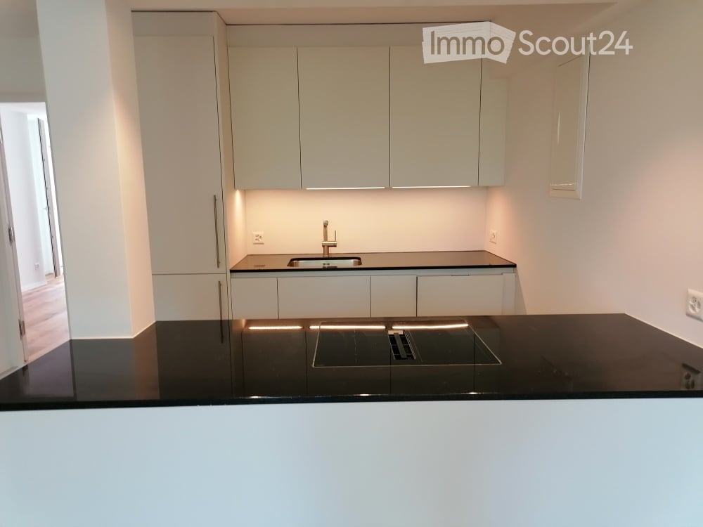 Modern kitchen with white cabinets, black countertops, and a built-in sink with a modern faucet.