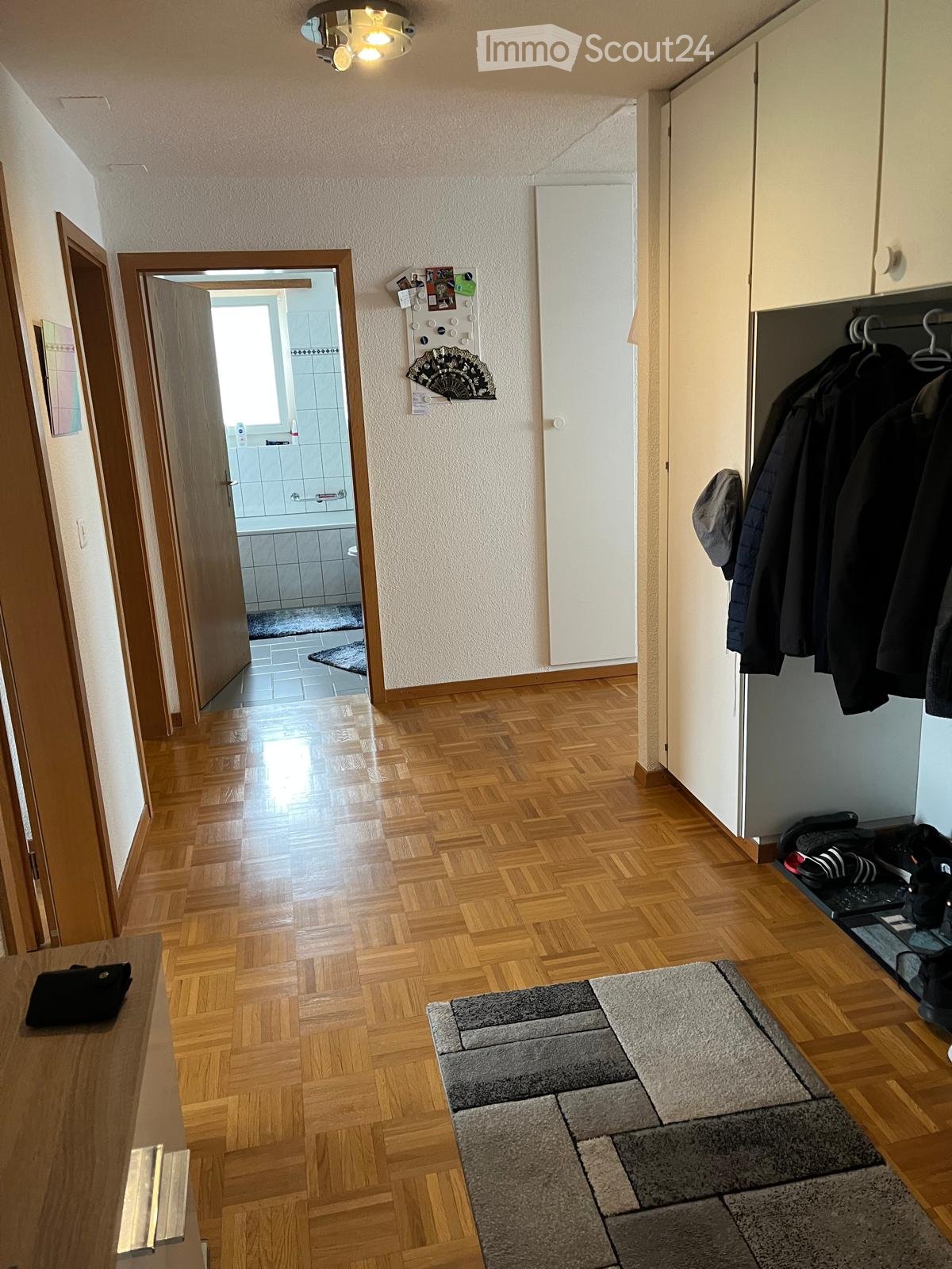 empty room with parquet floor, a closet, a bathroom, a hallway