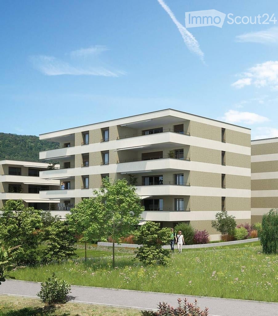 Modern multi-story residential building with balconies, surrounded by greenery and a well-maintained lawn.
