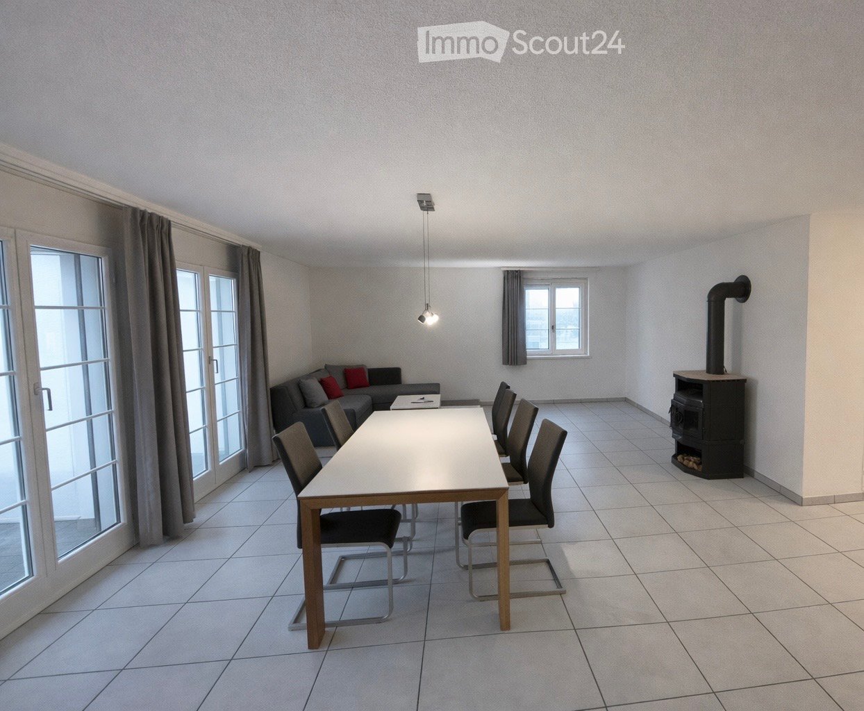 Bright room with tiled floor, large window, fireplace, sofa, dining table, and chairs.