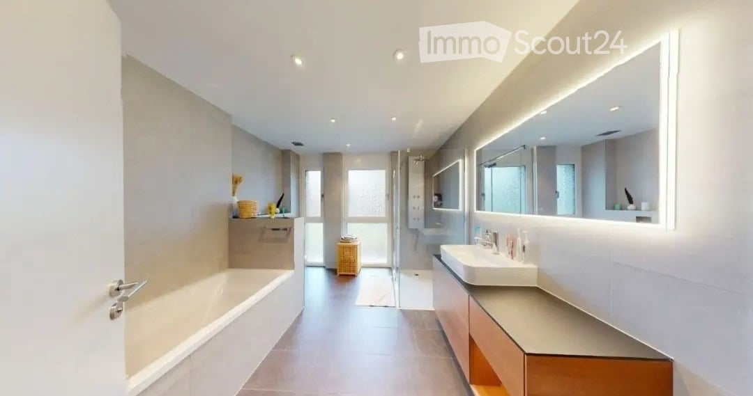 Modern bathroom with a bathtub, sink, large mirror, and built-in cabinets. The space features sleek, contemporary design with neutral tones and integrated lighting.