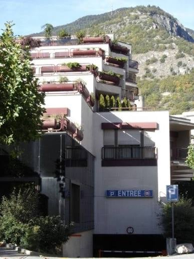 Multi-story residential building with balconies and a parking entrance sign.