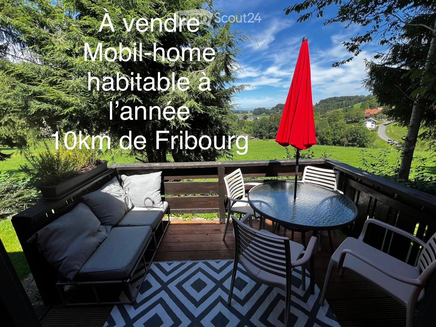Balcony with wooden decking, sofa, table, chairs, umbrella, and scenic countryside view.