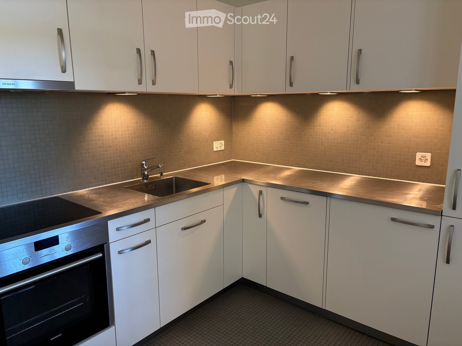 Modern kitchen with white cabinets, stainless steel appliances, and a sleek countertop.
