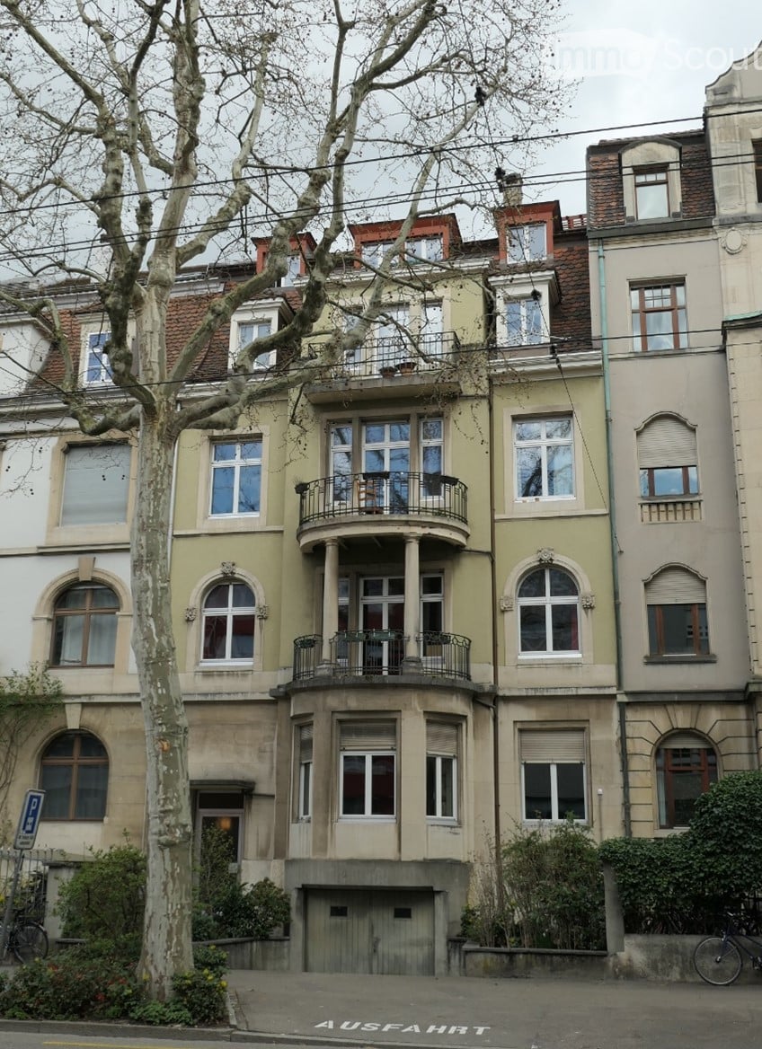 Multi-story residential building with balconies, large windows, and ornate architectural details.
