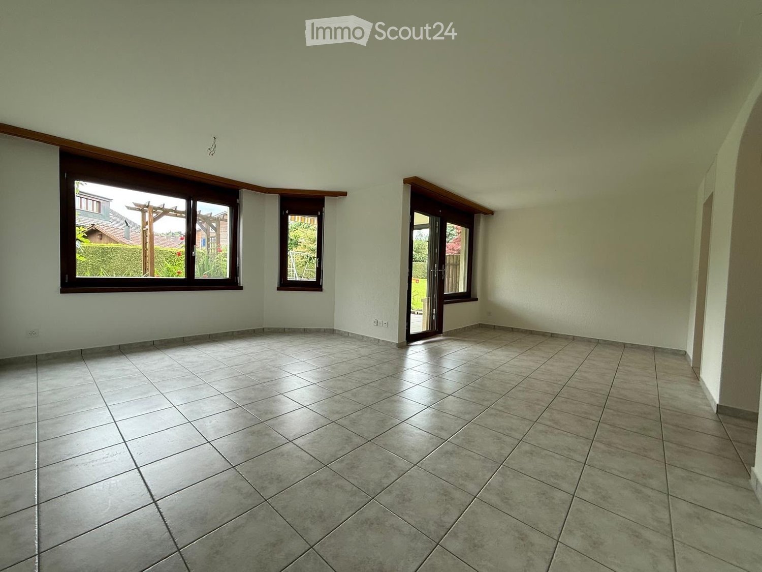 Empty room with tiled floor, large windows, and a door leading outside.