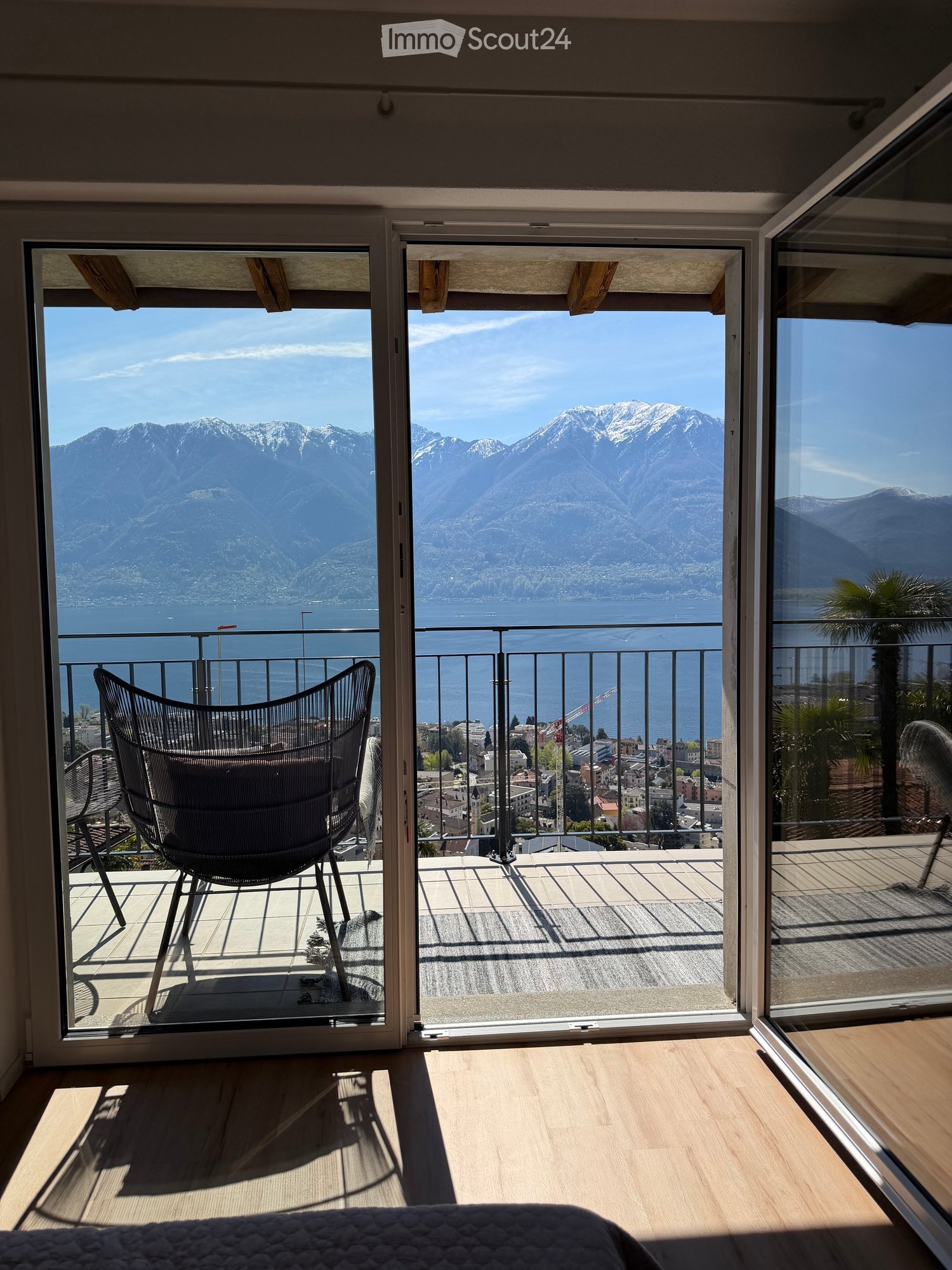 Balcony with a scenic mountain and lake view, featuring a single chair and a railing.
