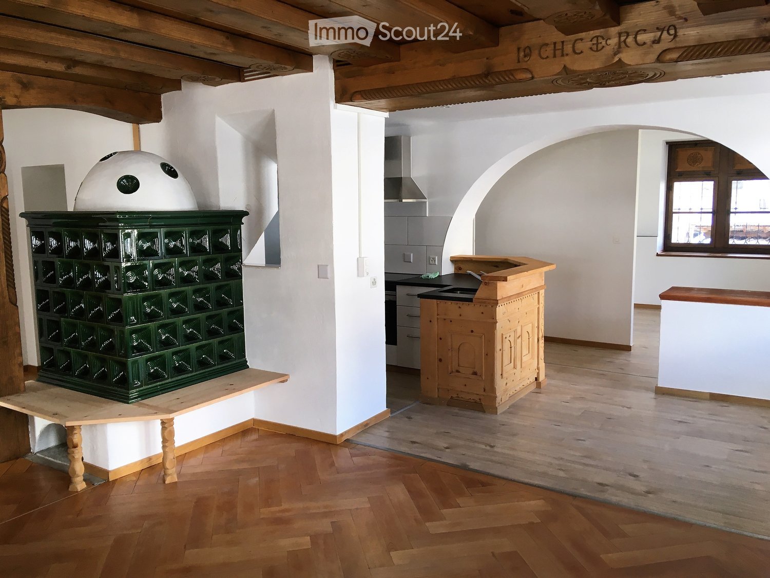 The kitchen features a wooden counter, sink, wooden cabinet, wooden table, wooden chair, and a wooden stove with a dome-shaped top.