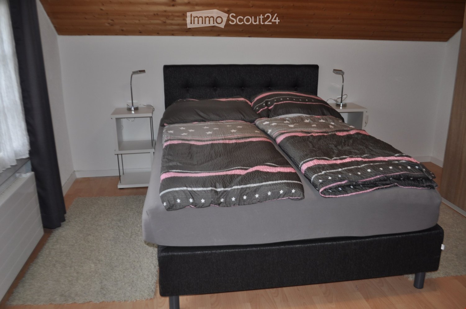 A neatly arranged bedroom with a double bed, nightstands, lamps, and a rug on the floor.