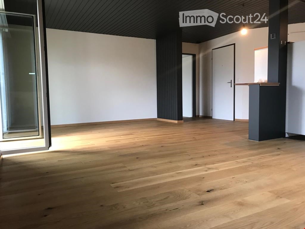 Empty room with wooden flooring, white walls, and large windows. No furniture or equipment present.