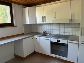 Bright kitchen with white cabinets, tiled backsplash, and stainless steel appliances.
