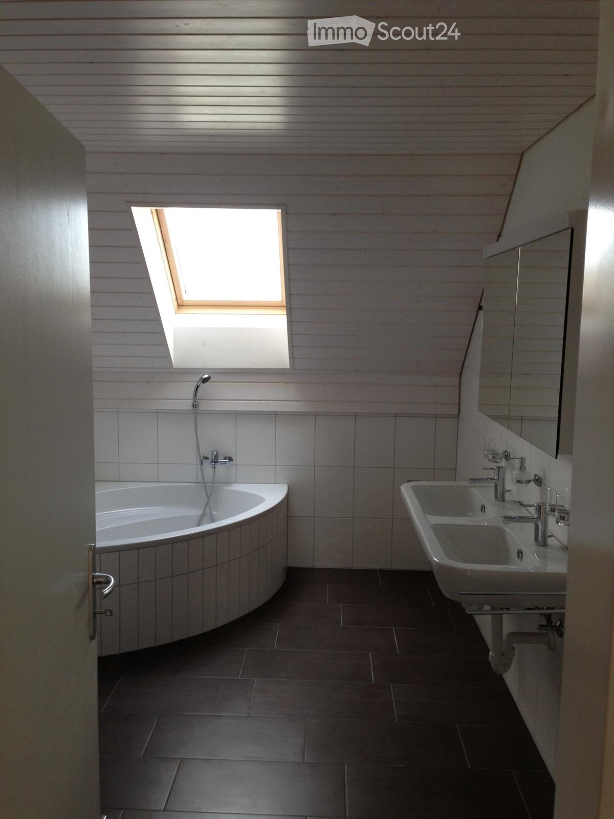Modern bathroom with a large window, bathtub, double sink, and mirror.