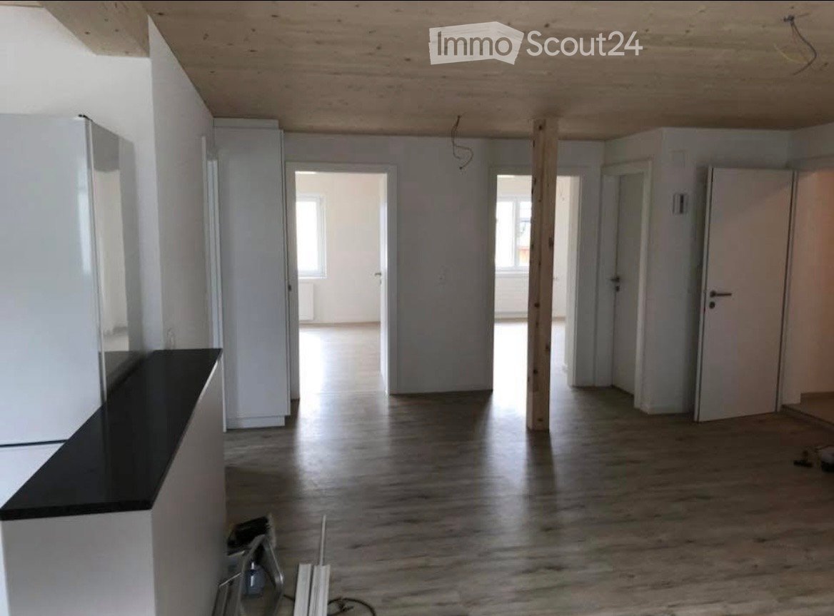 Empty room with wooden flooring, white walls, and several doors leading to other spaces. No furniture or equipment is present.