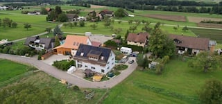 House complex with several buildings, swimming pool, green landscape, driveway, large garden