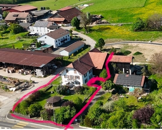 Aerial view of a rural residential area with multiple houses, barns, and open fields. The highlighted area outlines a specific property boundary.