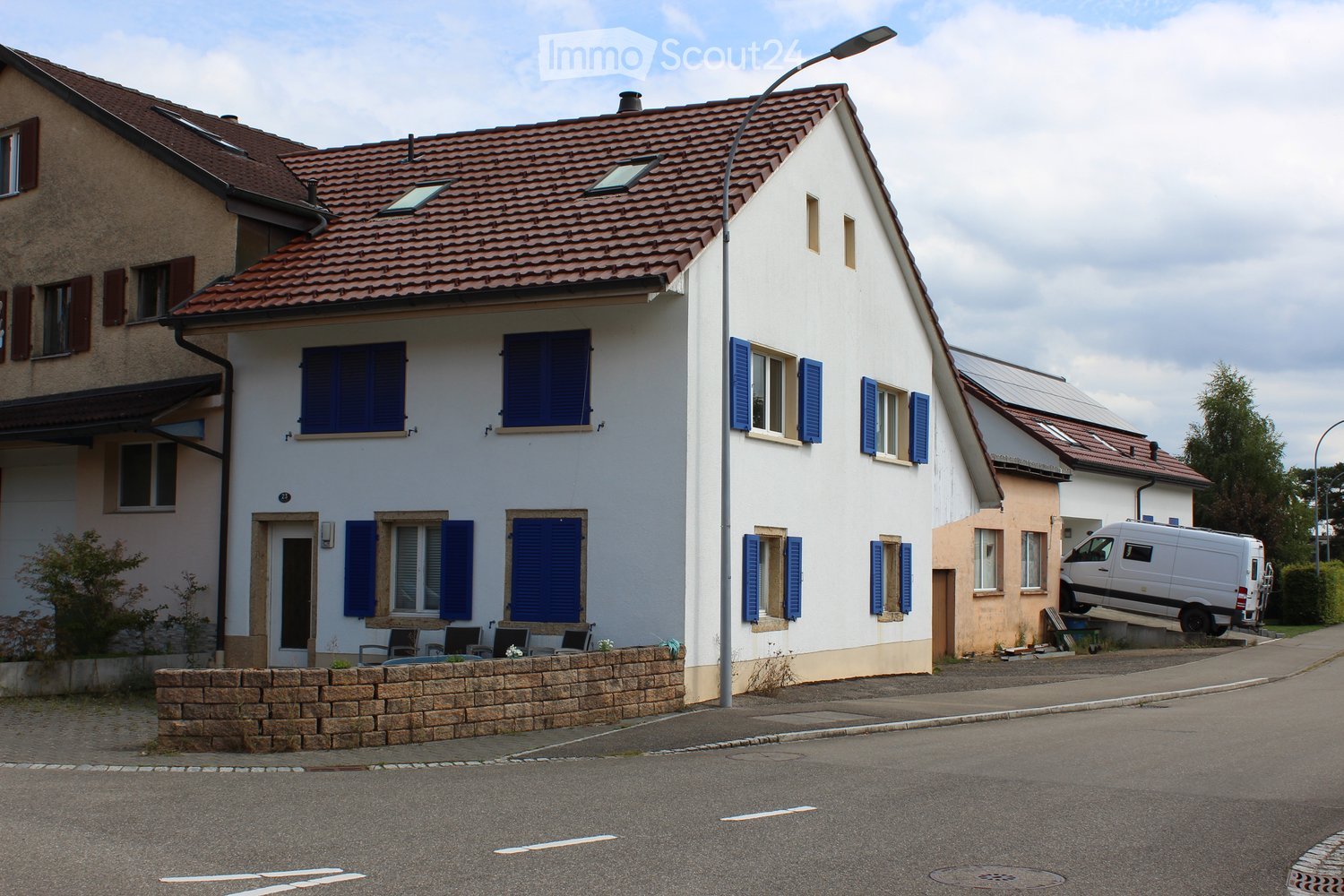3 story white house, red roof, blue shutters, solar panels on adjacent house