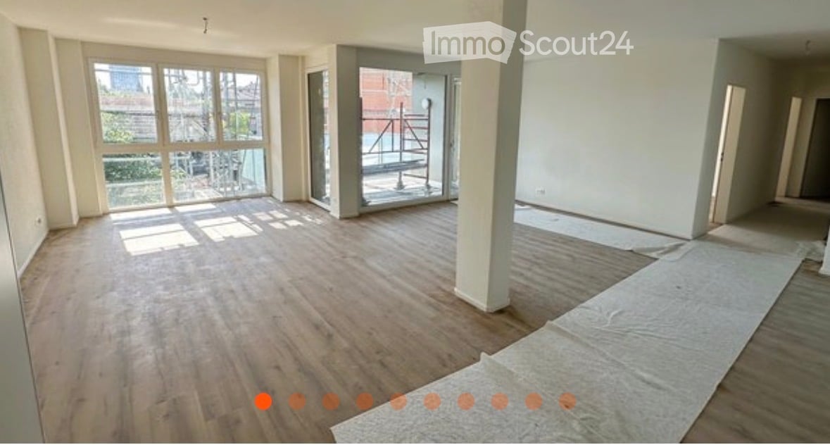 Empty room with wooden flooring, large windows, and a glass door leading to a balcony area. No furniture or equipment is present.
