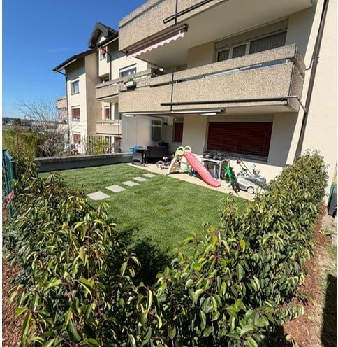 Well-maintained garden with artificial grass, small play area including a slide, and various outdoor furniture.