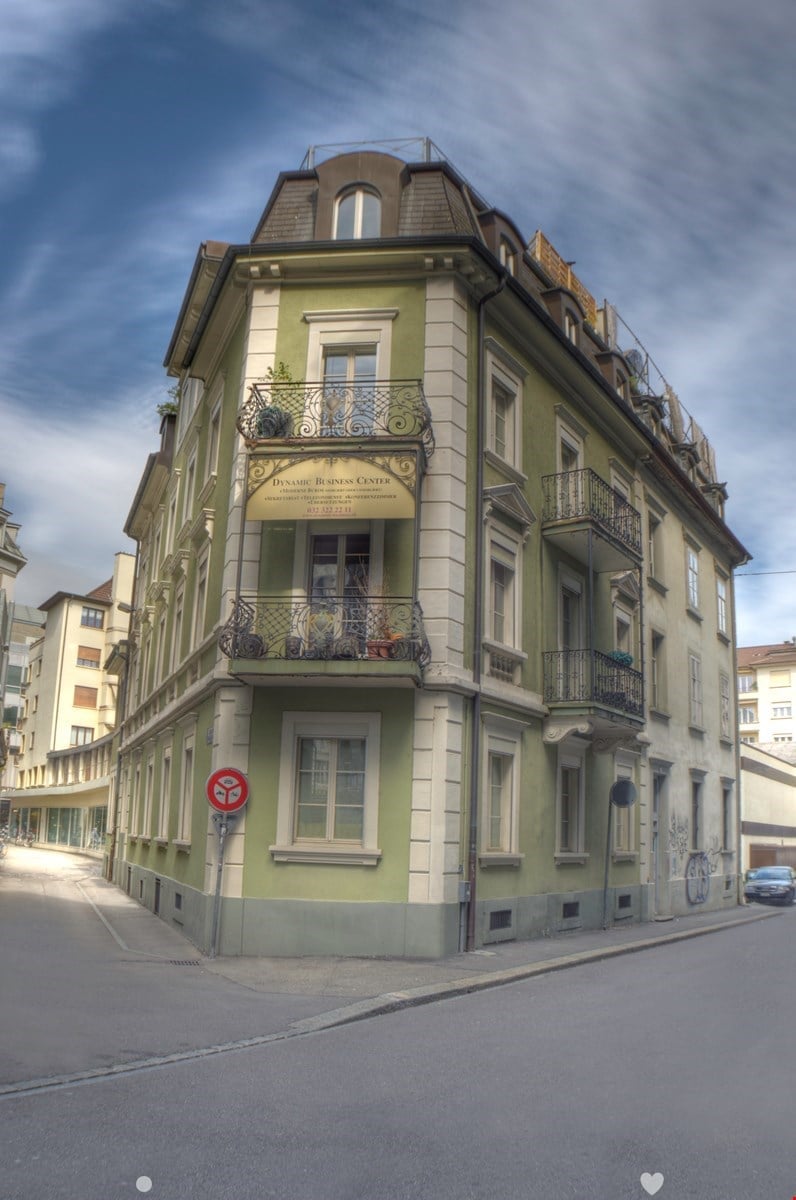 5 story green building with many balconies and terraces