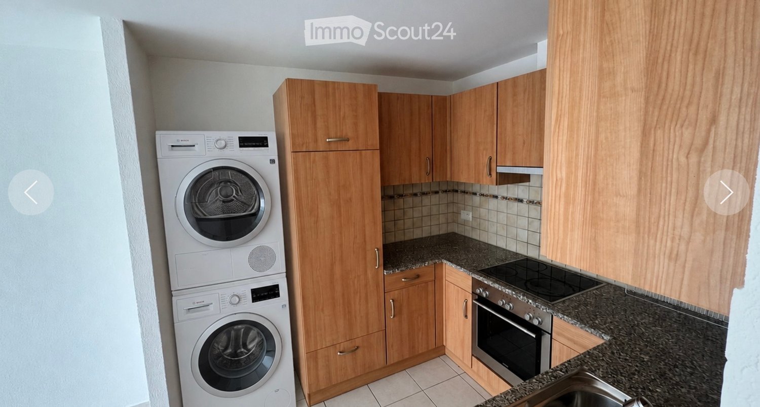 Modern kitchen with wooden cabinets, granite countertops, stainless steel appliances including an oven, stove, and washing machine.