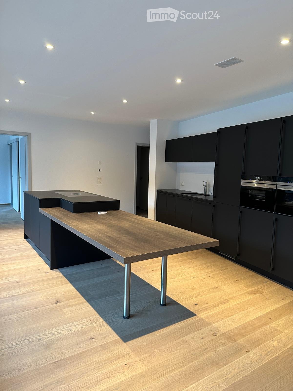 Modern kitchen with a wooden island, black cabinets, and stainless steel appliances.