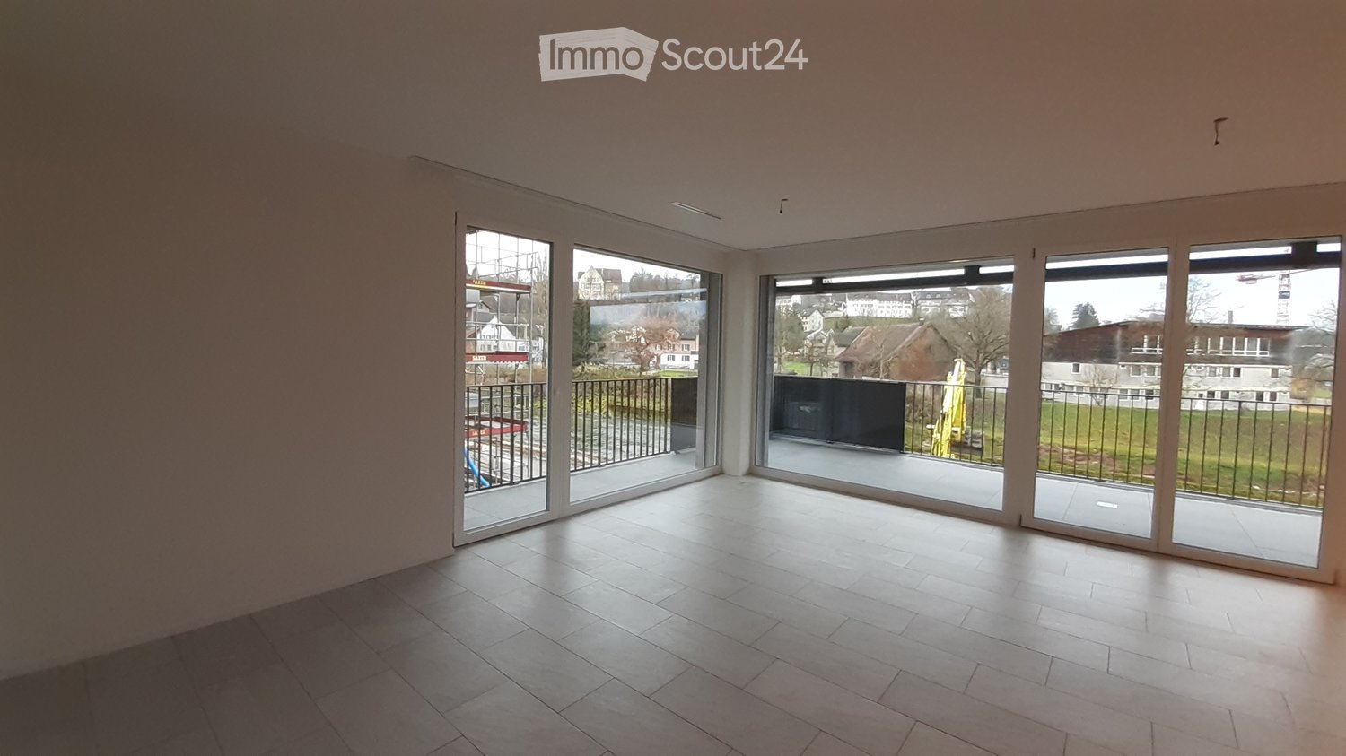 Empty room with large sliding glass doors leading to a balcony, tiled floor, and bright natural light.