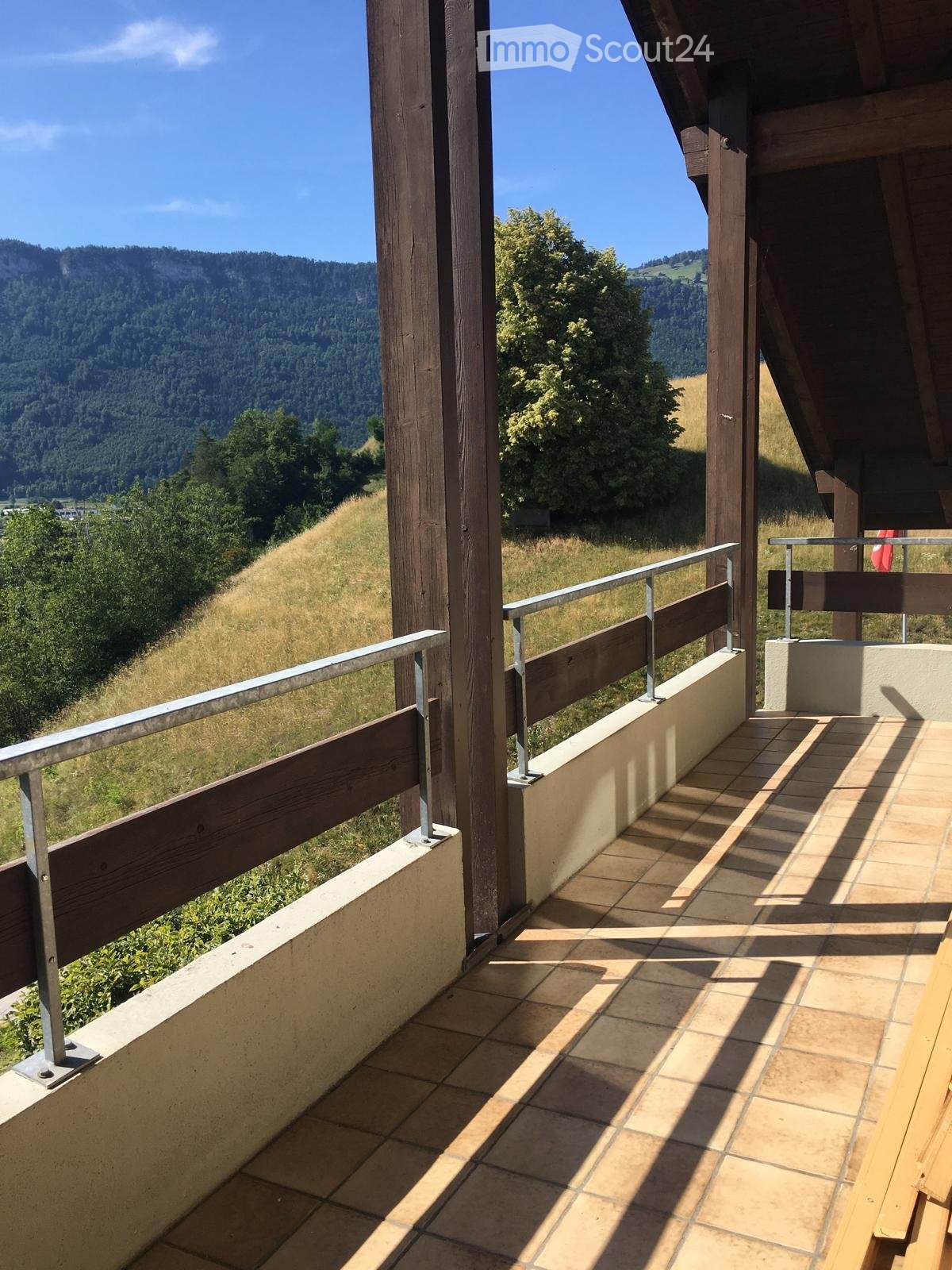 Balcony with tiled floor, wooden railing, and scenic mountain view.