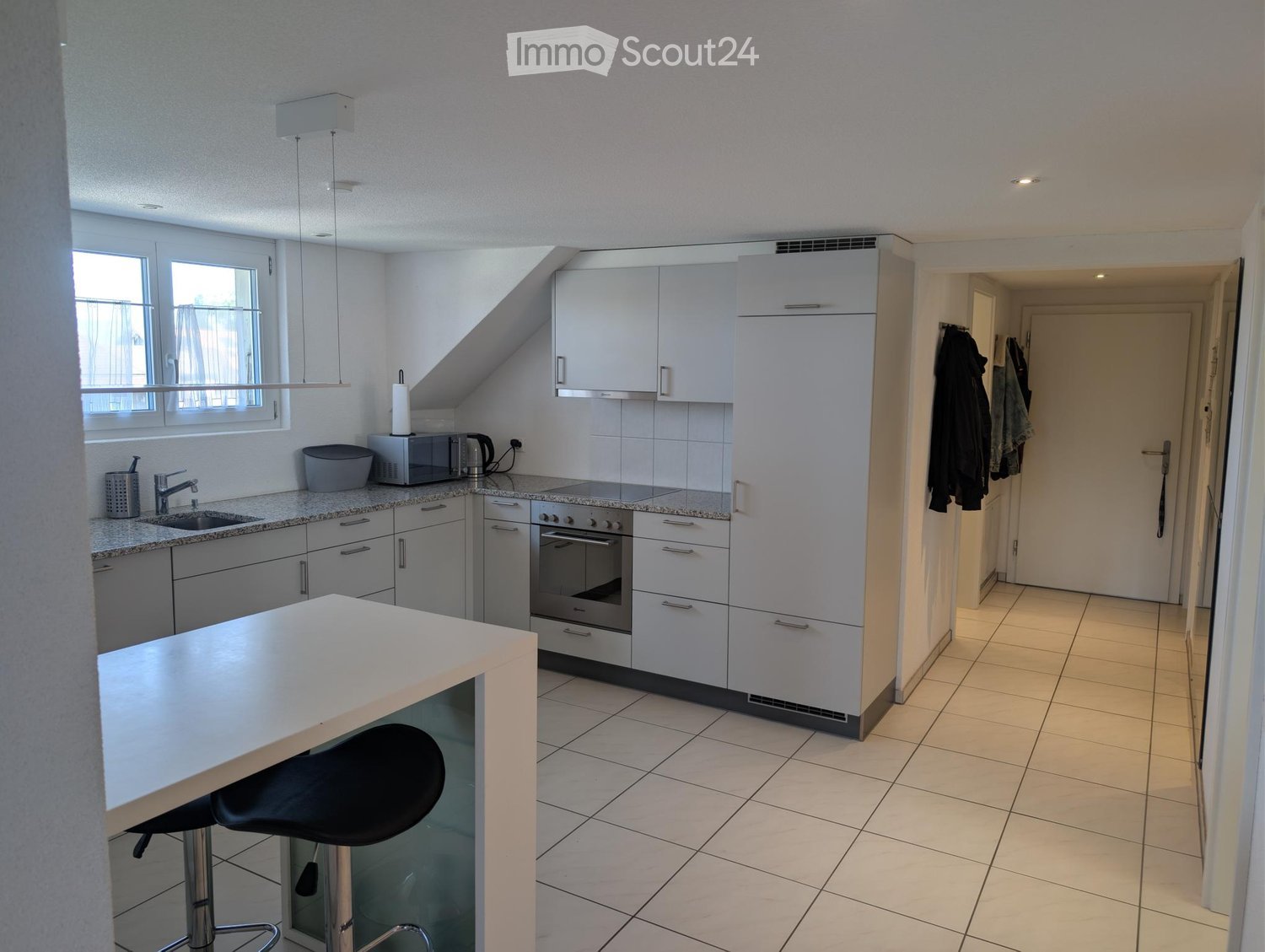 Modern kitchen with white cabinets, granite countertops, stainless steel appliances, and a bar stool.