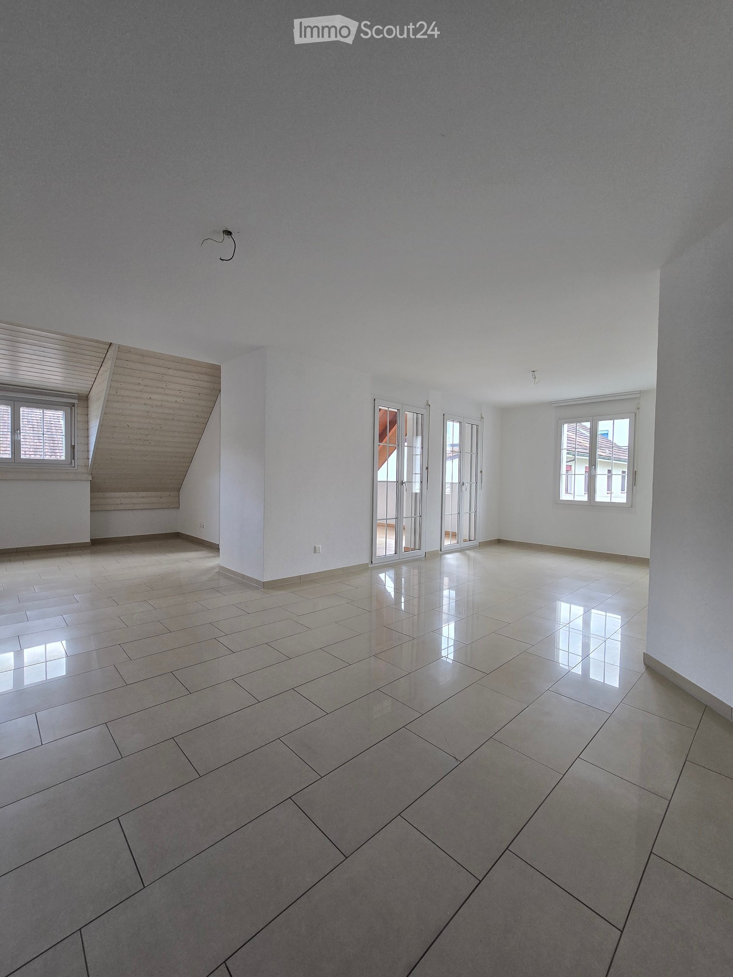 Empty room with white walls, tiled floor, and large windows. No furniture or equipment present.