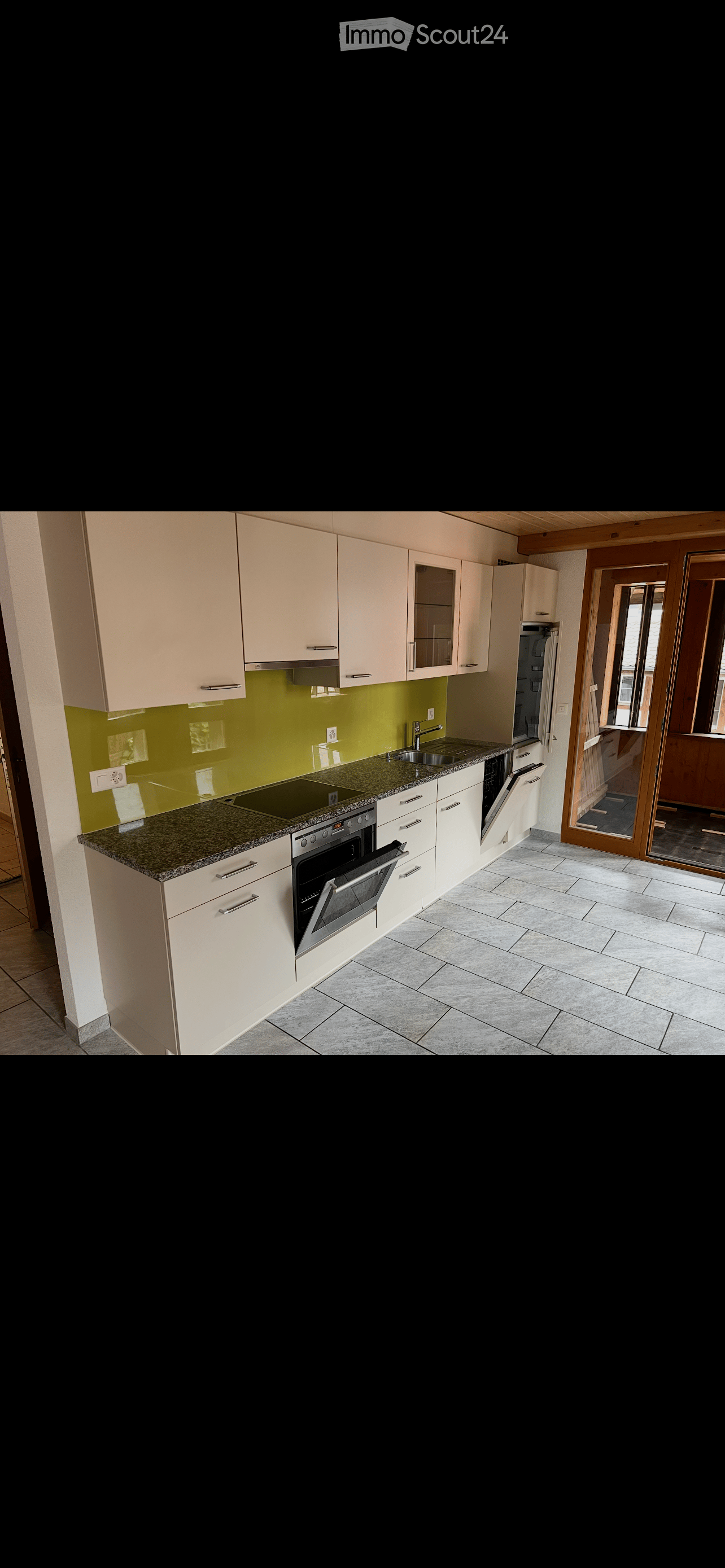 Modern kitchen with light-colored cabinets, granite countertop, stainless steel appliances, and a green backsplash.