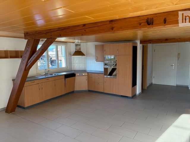 wooden cabinets, tiled floor, white countertops, stainless steel sink, oven, microwave, wooden beams, natural light