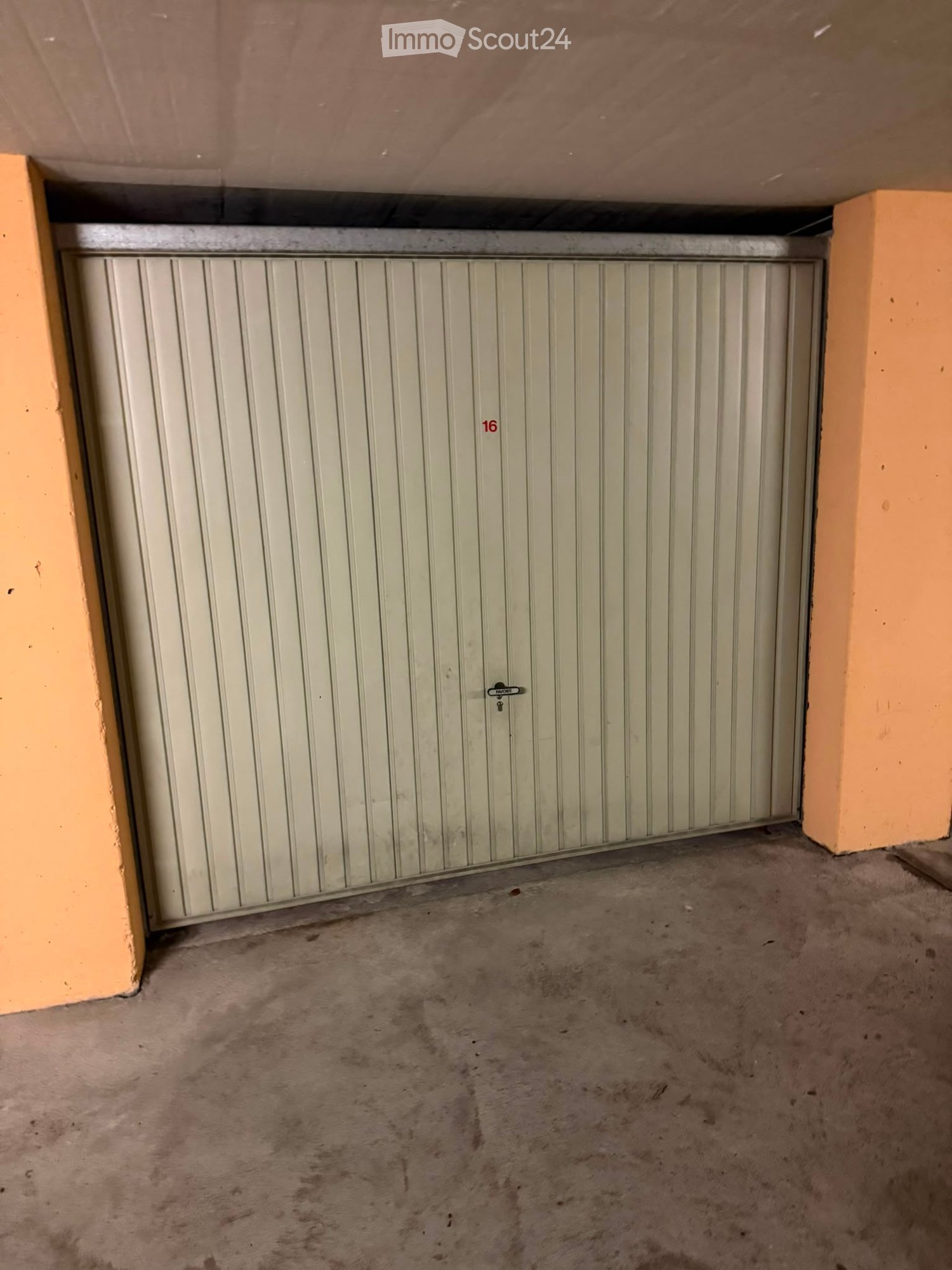 Empty garage space with a closed garage door, concrete floor, and surrounding walls.