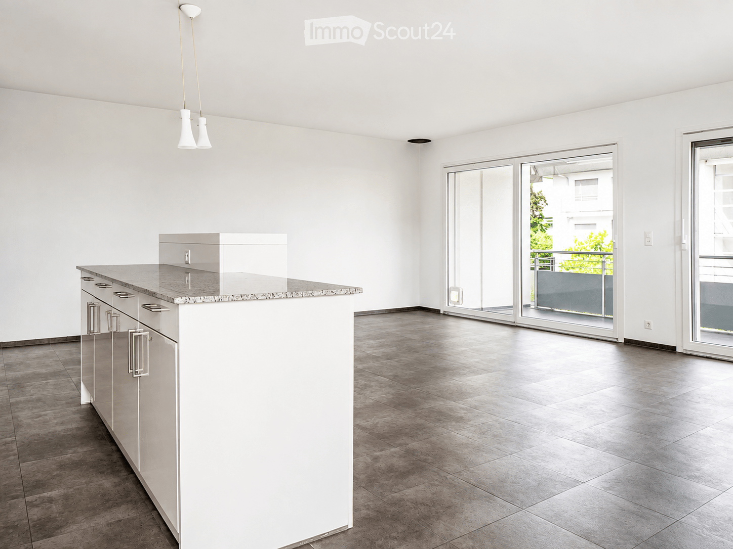 Empty kitchen with white cabinets, granite countertop, and large sliding glass doors leading to a balcony.