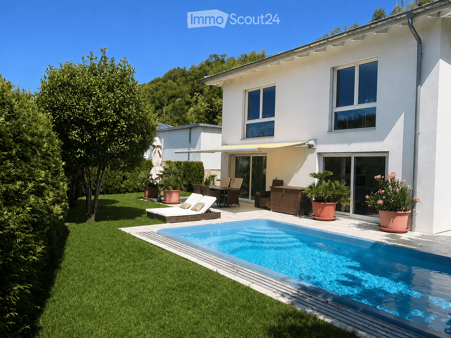 Modern outdoor area with a swimming pool, lounge chairs, dining set, potted plants, and a well-maintained lawn.