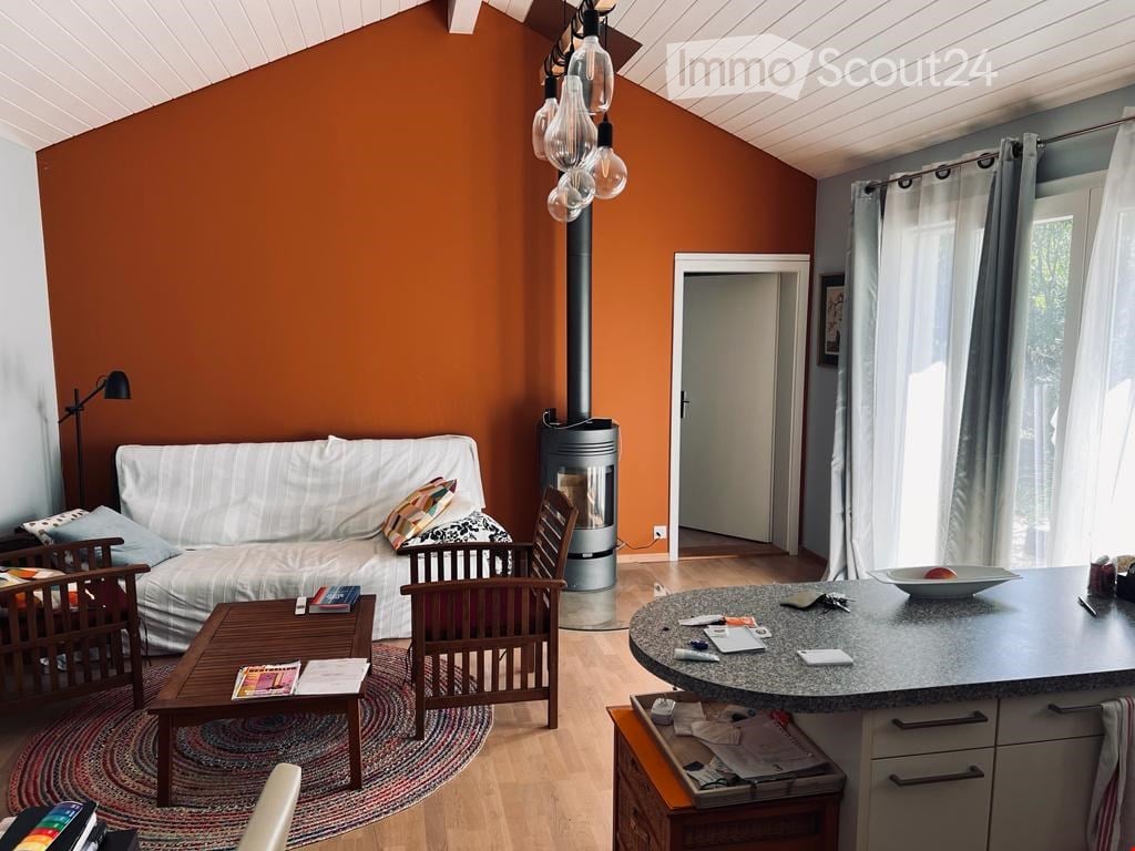 Orange walls, a white sofa with decorative pillows, a round wooden coffee table, a wooden chair, a fireplace, and a black lamp.