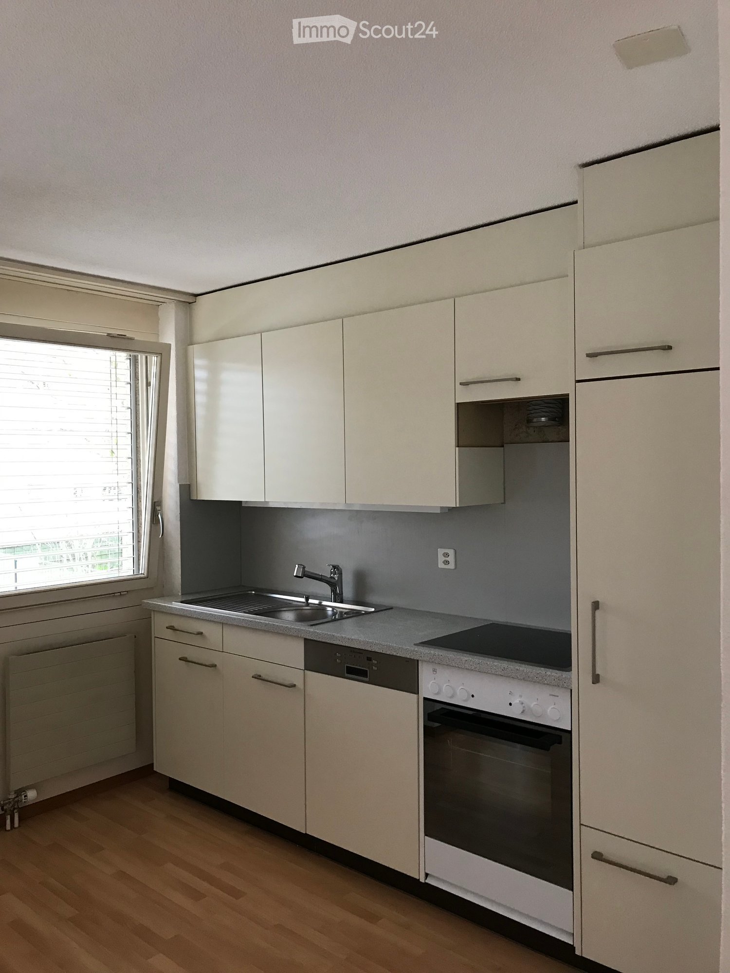 {"visible_features": ["Private washing machine", "Dishwasher"],    "type": "Room",    "description":"Modern white kitchen with wooden floor, undermount sink, oven, dishwasher, cabinets, window, gray wall, and electric outlet",    "localized_description
