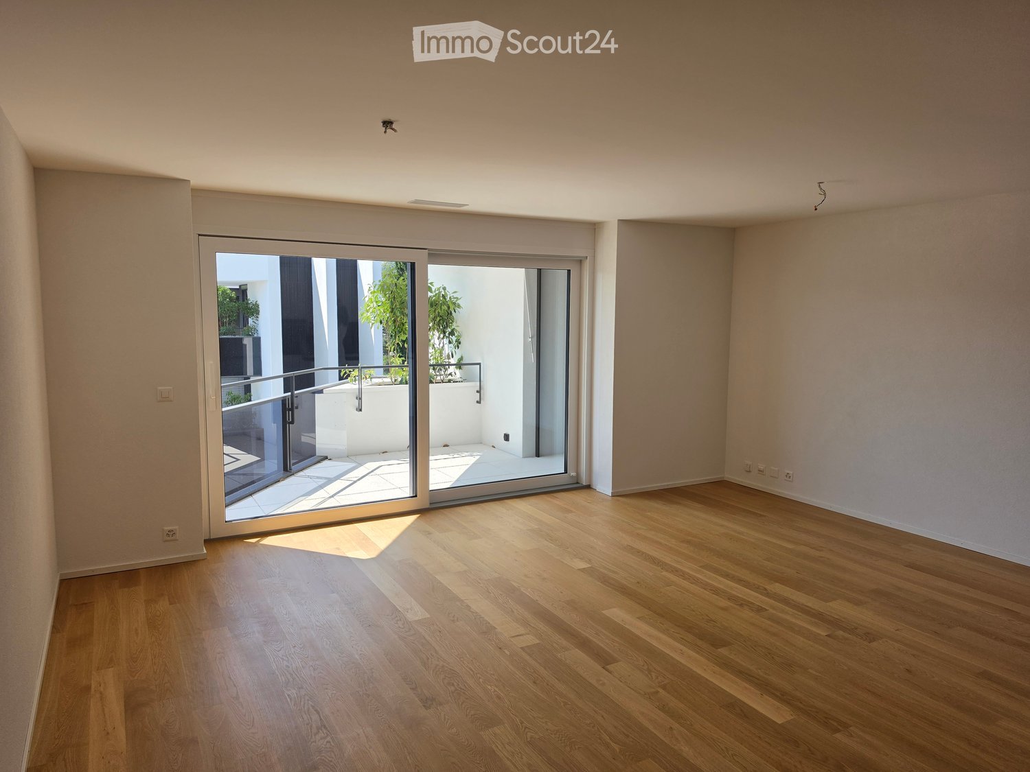 Empty room with wooden flooring and large sliding glass doors leading to a balcony area.