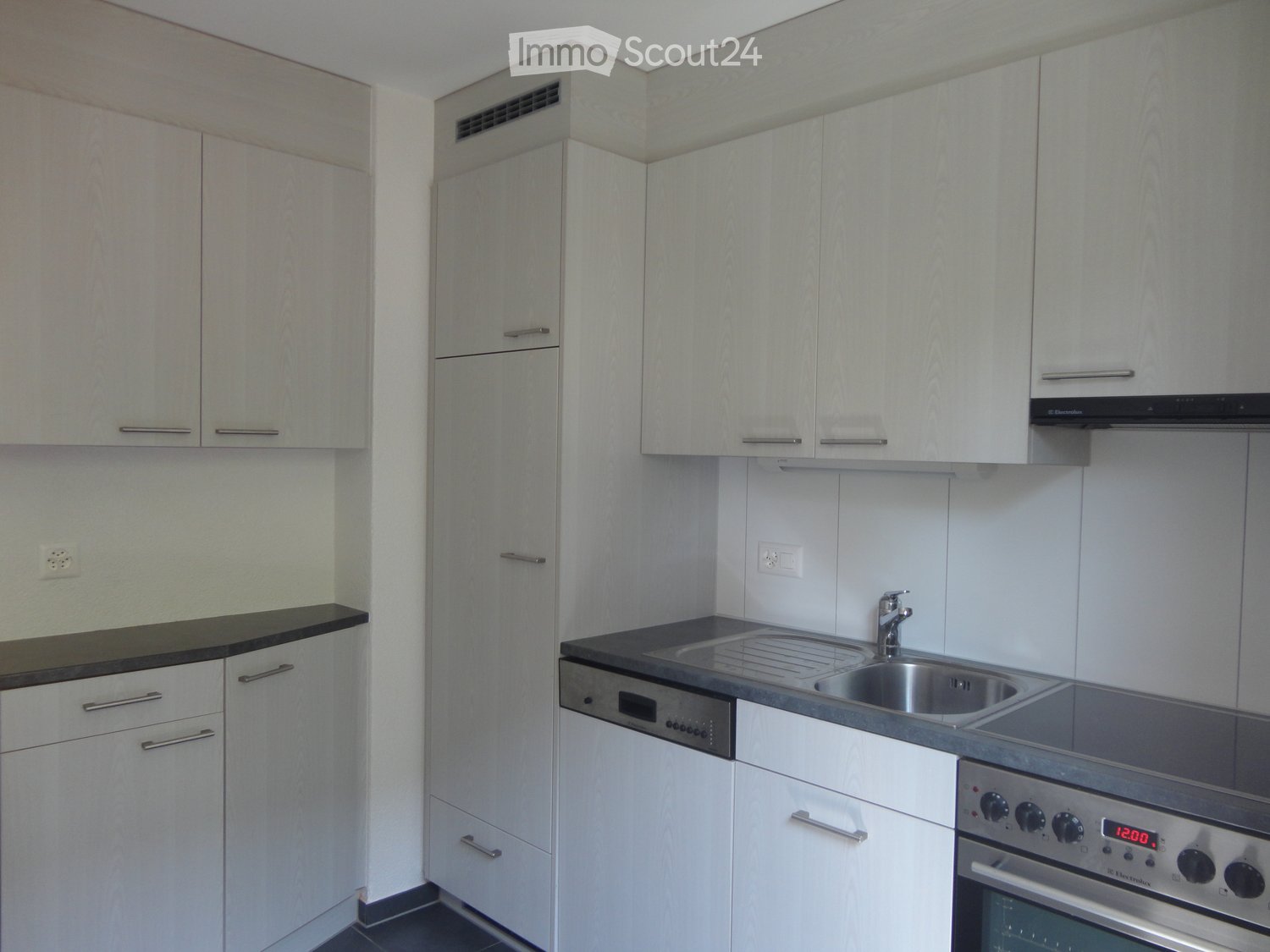 Modern kitchen with white cabinets, stainless steel sink, oven, and dishwasher.
