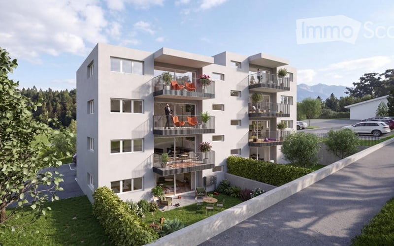 Modern multi-story residential building with balconies, surrounded by greenery and parking area.