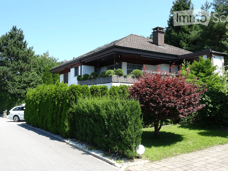 Detached house, white exterior, brown roof, balcony, garden, hedge, driveway, car parked