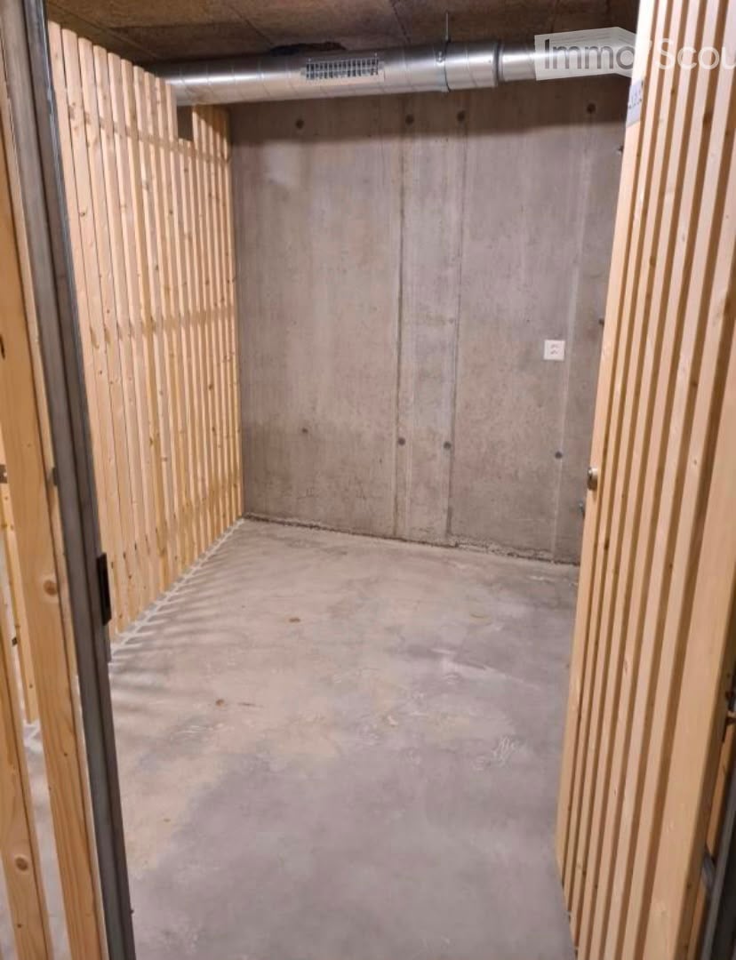 Empty room with unfinished concrete walls and floor, wooden framing on the sides, and exposed ductwork on the ceiling.